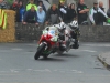 The crowd watch on as Michael Dunlop leads older brother William into Athea Village in a wet Supersport race in 2011