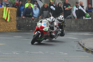 The crowd watch on as Michael Dunlop leads older brother William into Athea Village in a wet Supersport race in 2011